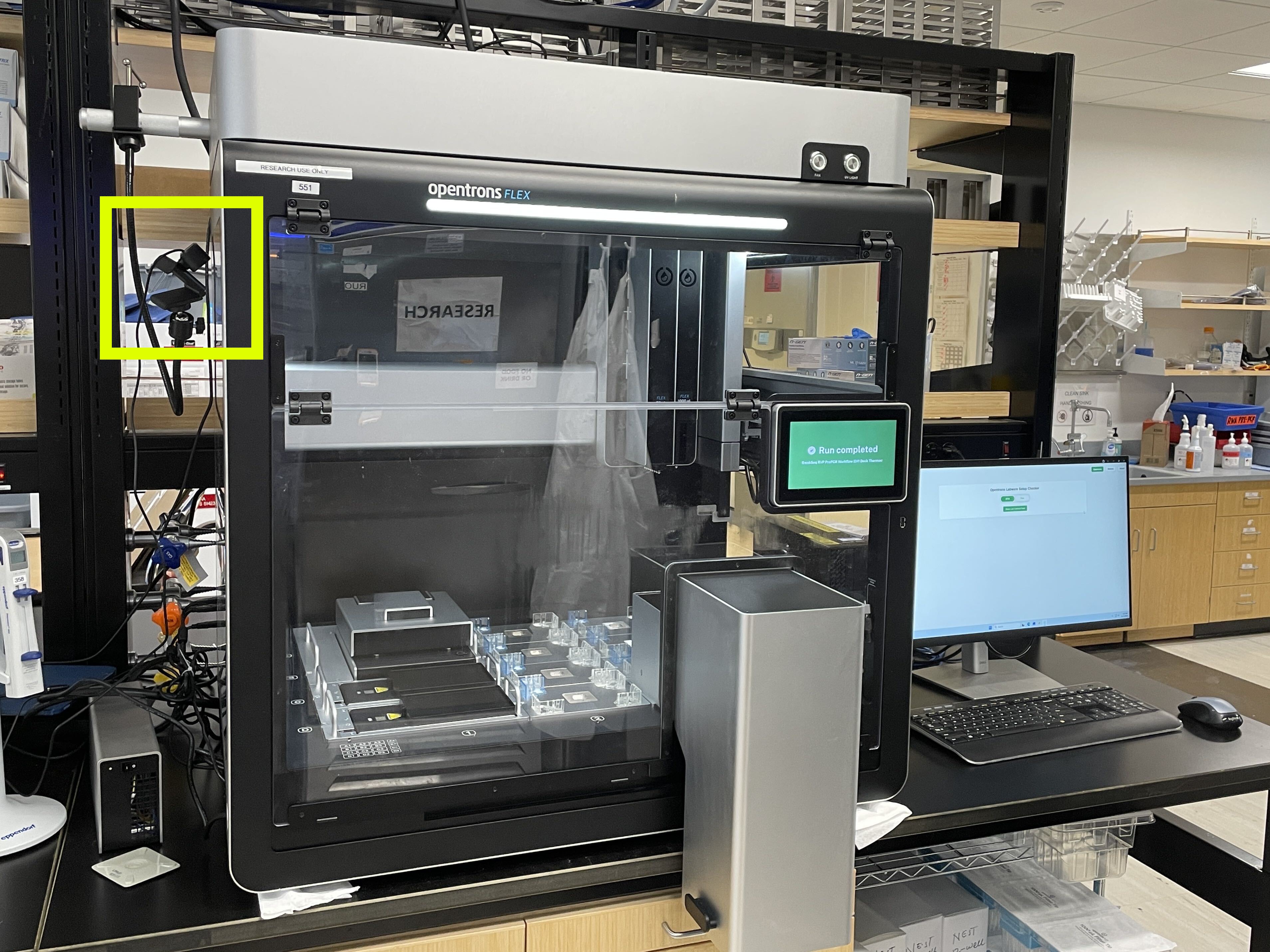 Laboratory liquid-handling robot with an external camera highlighted and a separate computer running the setup checker.