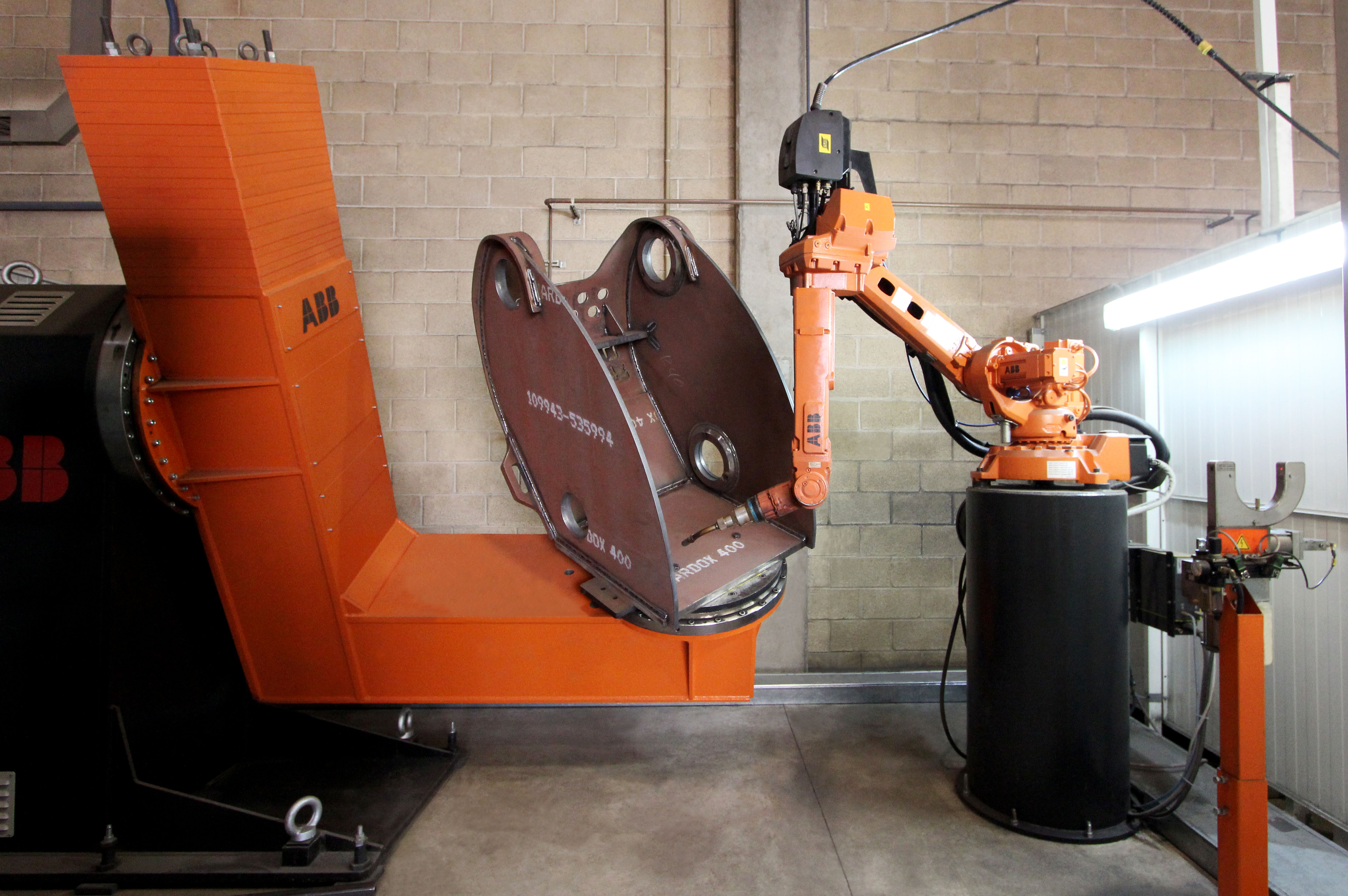 Historical ABB industrial welding robot working on a metal housing.