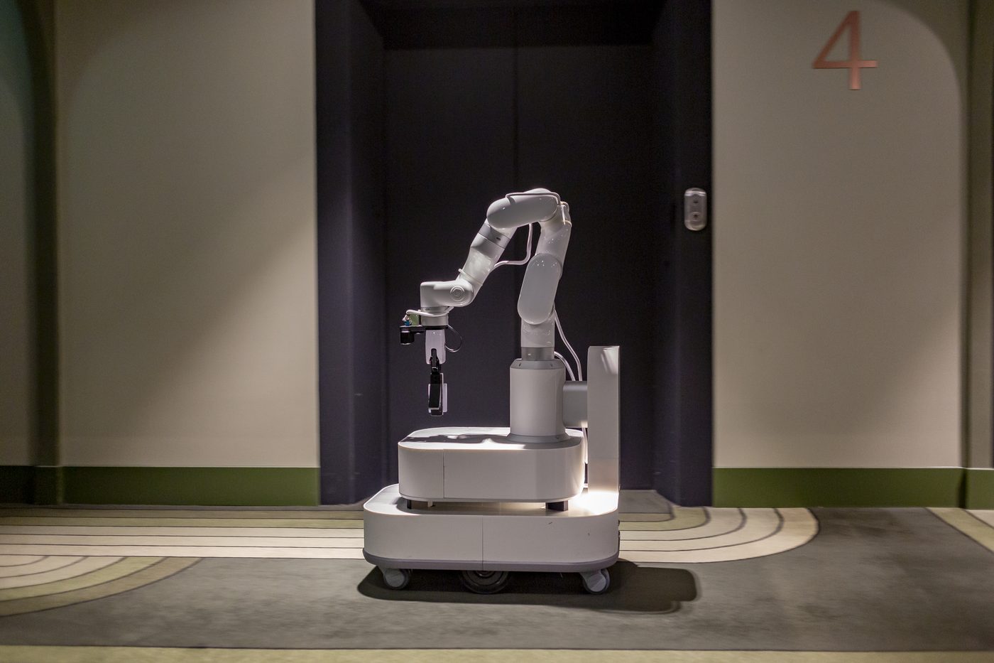 Bellboy mobile manipulator standing in a hotel guest-floor corridor.