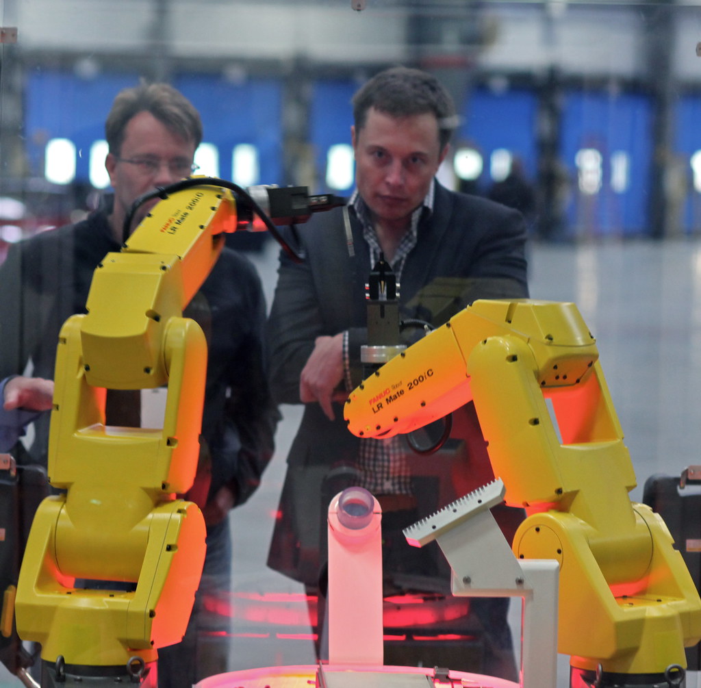 Two yellow FANUC robot arms perform an assembly demonstration in 2010.