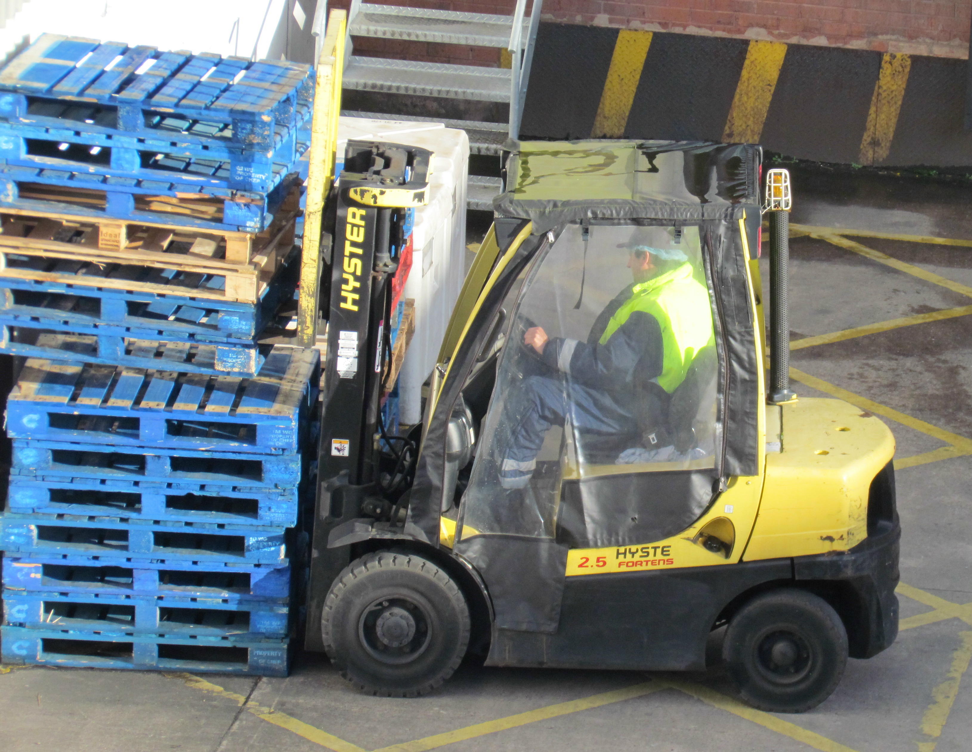 A manually operated forklift beside stacked pallets in 2012.